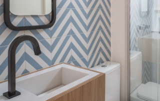 lavabo azulejo azul chevron torneira preta espelho arredondado preto cuba branca saia amadeirada