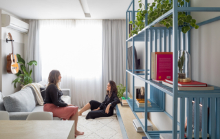 mulheres sentadas em sala de quitinete estante azul metal